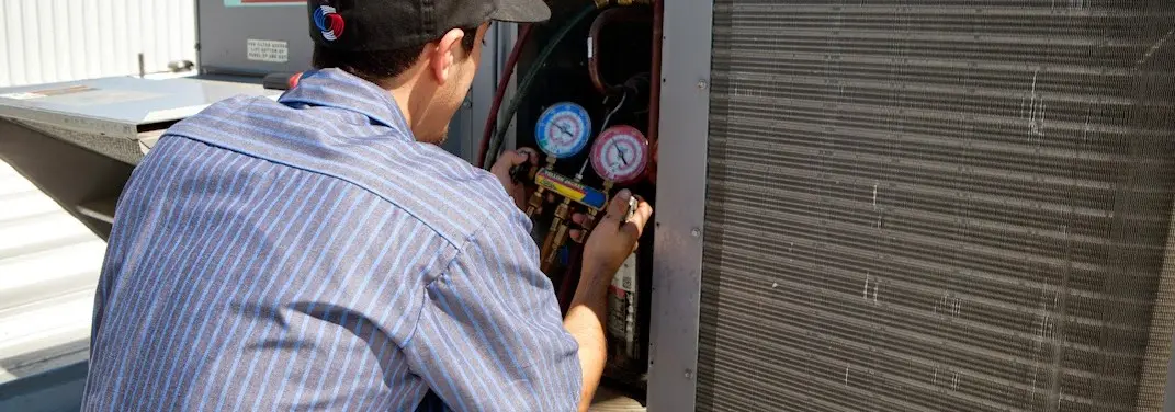HVAC technician servicing a condenser unit in Peppermill Village